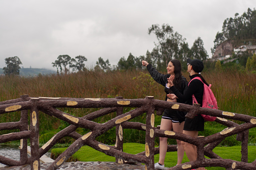 a daughter and her mother walking on a wooden bridgetalking and laughing about women's things and sharing a happy moment between women. women's day. High quality photo