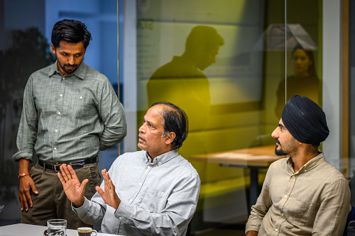 Middle eastern male investors arguing while sitting in meeting room at night, medium shot