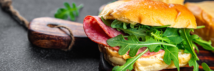 sandwich bun, sausage, salami, arugula, green lettuce ready to eat cooking appetizer meal food snack on the table copy space food background rustic top view