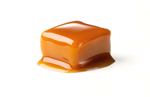 A closeup of melting, delicious, sugary caramel tablet on white background