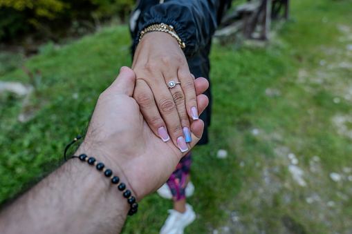 A loving couple holds hands, proudly displaying the engagement ring on the bride-to-be's finger