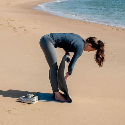 Athletic young woman doing yoga exercise on the beach.