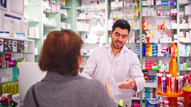 Adult woman buying medicine from a Male pharmacist while standing at the counter