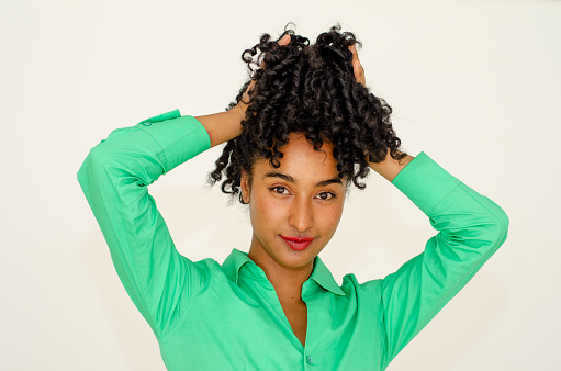 portrait of beautiful black woman in casual clothes and playing with her hair in white background