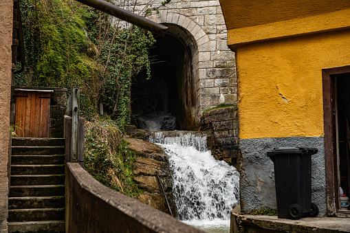 A small picturesque waterfall cascading  underneath a bridge in Hallstatt, Austria