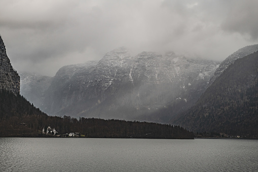 The majestic snow-capped mountains loom over a pristine mountain lake in Hallstatt, Austria