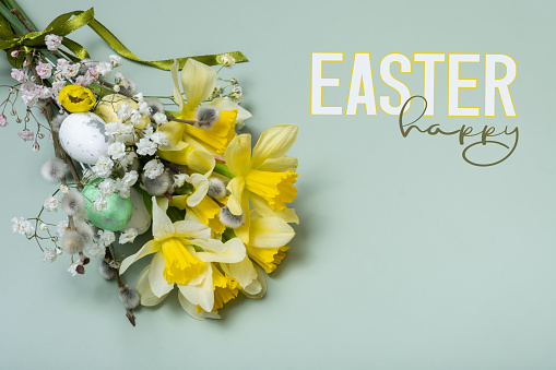 Easter spring bouquet with daffodils and willow on green background with Happy Easter text