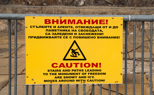 A yellow caution sign near The Liberty Memorial, also known as the Shipka Monument in Bulgaria.