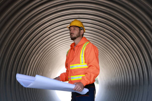 istock Mechanical engineer or technician with reflect safety jacket hold blueprint working on construction site 1883020568