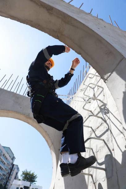 Happy Latin American construction worker wearing a safety harness at a building site
