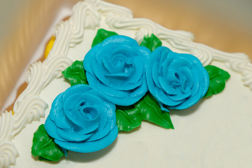 Closeup of blue creamy flowers on a white cake