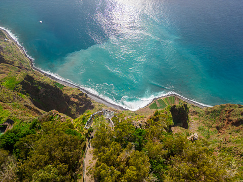 An aerial shot of a green shoreline with turquoise waters of the ocean. Madeira, Portugal