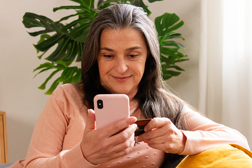 Portrait of a senior woman using mobile phone while sitting at home