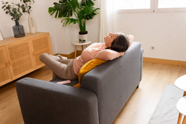 istock happy young woman lying on sofa at home and looking away from camera 1883157749