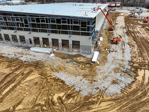 A bird's-eye view of the foundational groundwork of a vast industrial facility, with materials and earthmovers dotting the early construction