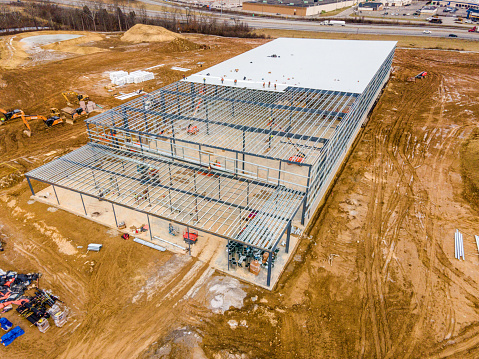 A bird's-eye view of the foundational groundwork of a vast industrial facility, with materials and earthmovers dotting the early construction