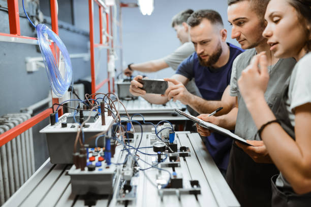 istock Male Teacher Photographing Students While They Operate PLC Devices 1883188980