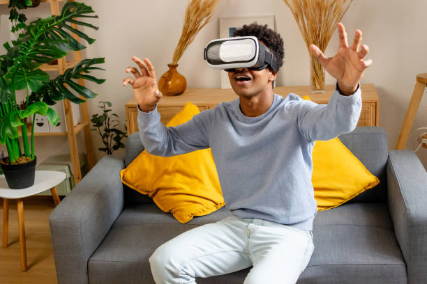 istock happy african american man in vr headset gesturing while sitting on sofa at home 1883189491