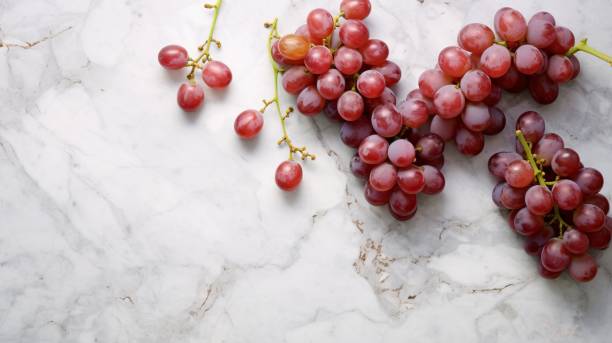 istock Overhead view of red grapes on a light marble tabletop 1883190522
