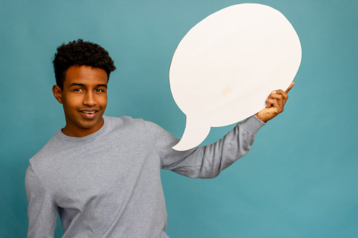 Young african american man holding a speech bubble on blue background