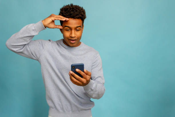 istock Surprised african american young man looking at mobile phone screen, isolated on blue background 1883191551