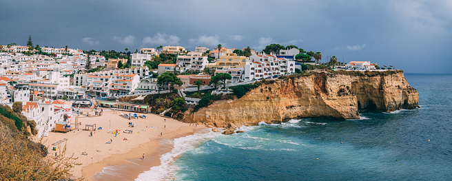 Algarve, Portugal – December 17, 2020: Carvoeiro fishing village with beautiful beach in Algarve, Portugal. View of beach in Carvoeiro town with colorful houses on coast of Portugal. Praia