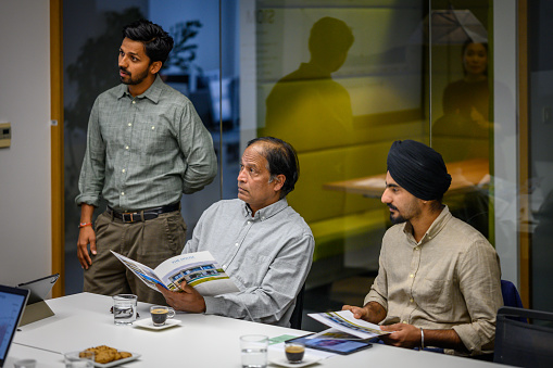 Indian male investors arguing while sitting in meeting room at night, medium shot