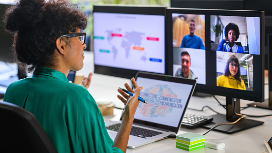 Female business analyst discussing global revenue chart with remote workers team in video call, back side view