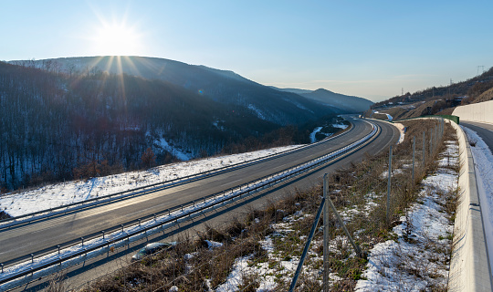 An empty two-lane highway. Winter scene. Empty asphalt road in rural landscape at sunset with blue clouds. Asphalt highway road with beautiful blue sky in pastoral rural environment.