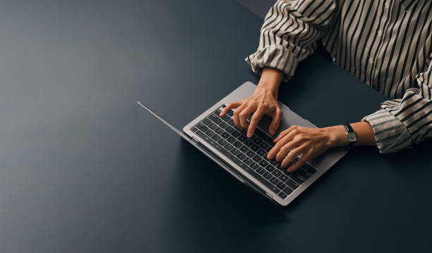 An Unrecognizable Businesswoman Working In Her Office On Her Computer A from above view of an unrecognizable Caucasian copywriter typing on her laptop while sitting at her office desk. (copy space) one person stock pictures, royalty-free photos & images