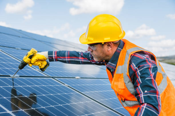 istock Solar Panel Installation: Technician Man Working with Drill on Roof of Factory 1883395164