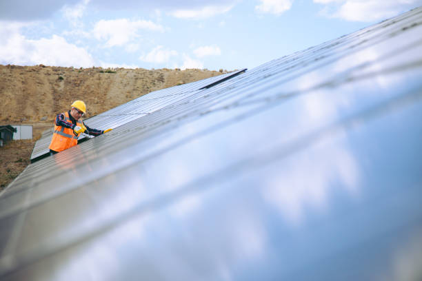 istock Solar Panel Installation: Technician Man Working with Drill on Roof of Factory 1883397218