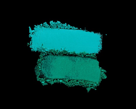 Green turquoise blue cosmetic smeared eye shadow swatch isolated on black background