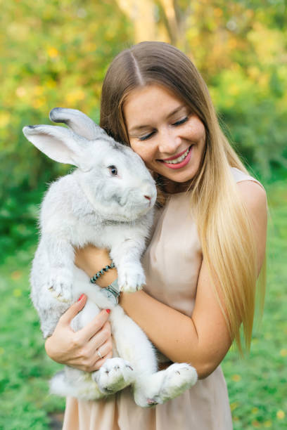 istock Pretty young woman long-haired hug cute rabbit on summer day 1883409780