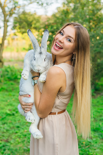 Woman with pet rabbit. Happy woman holding cute fluffy bunny.