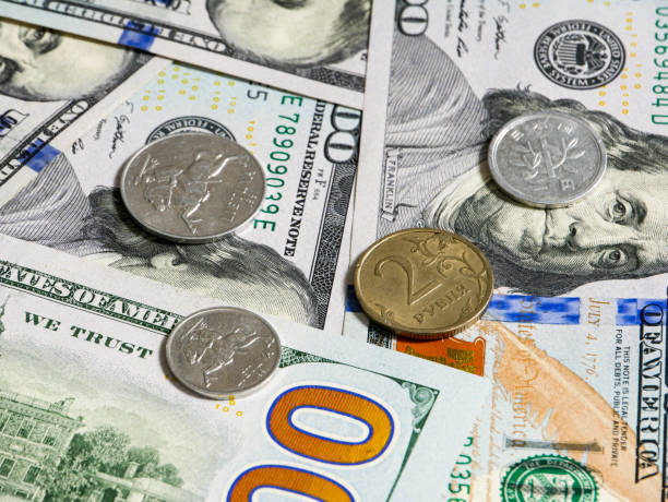 istock Coins from different countries are on American 100 dollar bills. 1883412444