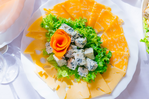 top view of a plate with cheese slices and lettuce. different types of cheese. wedding banquet.