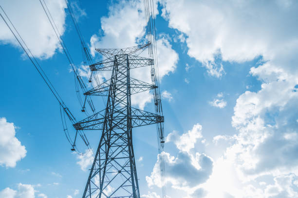 istock High voltage power line components and electrical equipment against a sunny background with white clouds and a blue sky. 1883440323