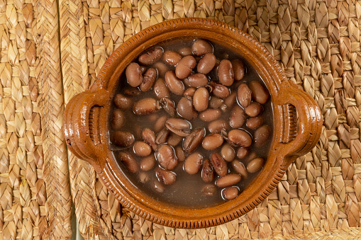 Beans from the pot, a typical Mexican dish, boiled beans with salt, water, on a clay plate.