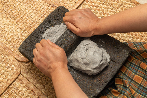 Young woman's hands, grinding dough in the metate for the elaboration of blue tortillas, which is a typical Mexican food, in the native towns the women are in charge of doing that task.