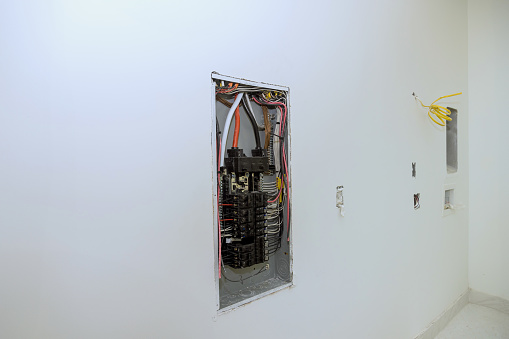 Electrical power control panel switch box is mounted to wooden frame beams on wall with circuit breaker mounted in it