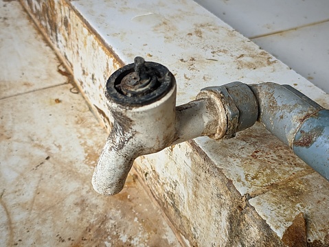The water faucet is damaged and dirty and white in color