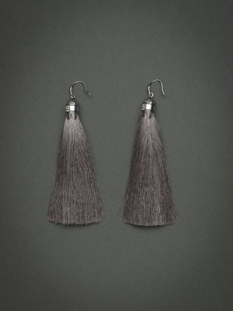 istock Women's silver earrings with gray threads on a gray background. 1883659694