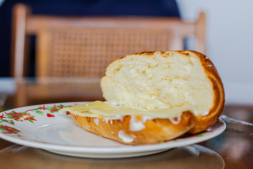 baker showing an open loaf of a sandwitch with mayonnaise and cheese for breakfast on a plate on a table