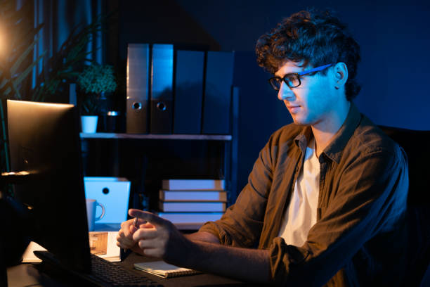 istock Businessman concentrating on pc on project at neon light office. Gusher. 1883737035
