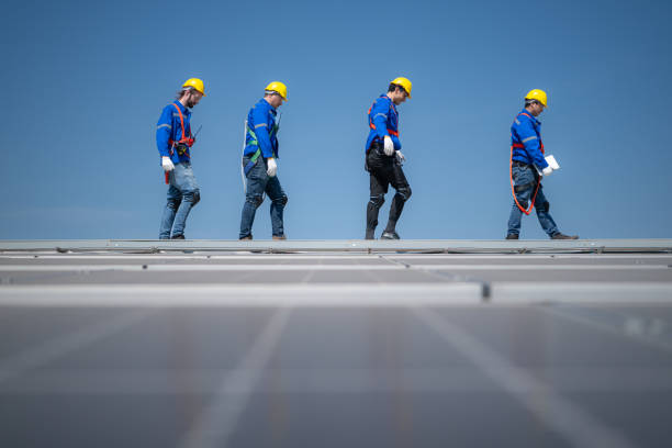 Group of engineers standing on solar panels with blue sky in the background