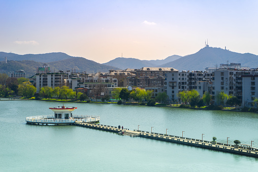 Peaceful scene along the lakeside in Xiangyang, Hubei Province, China. Set against the backdrop of picturesque marinas, cityscapes and mountains.