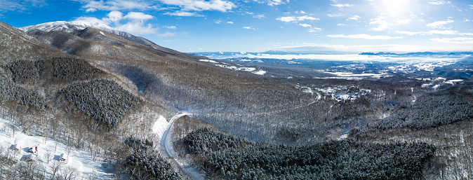An aerial wide panorama view of a  countryside mountain snow covered road in Iwate Prefecture in Japan.