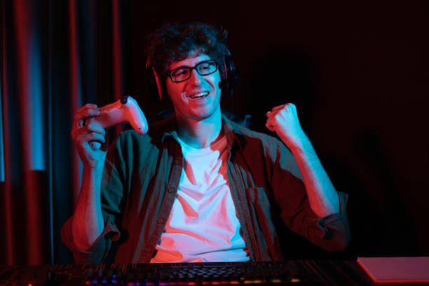istock Smiling streamer winning with joystick, focusing Esport team on pc. Gusher. 1883847646