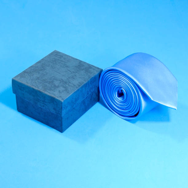 istock Blue tie rolled with gift box with blue background close-up view single object 1883848158
